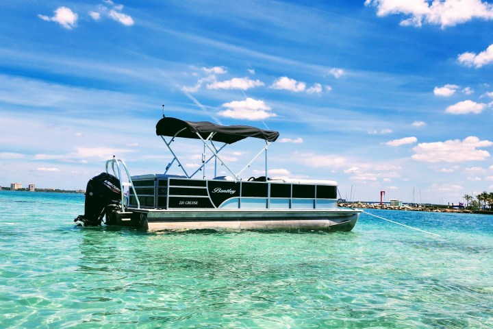 A 22-foot pontoon boat with a bimini top anchored in the waters near Sarasota, Florida.